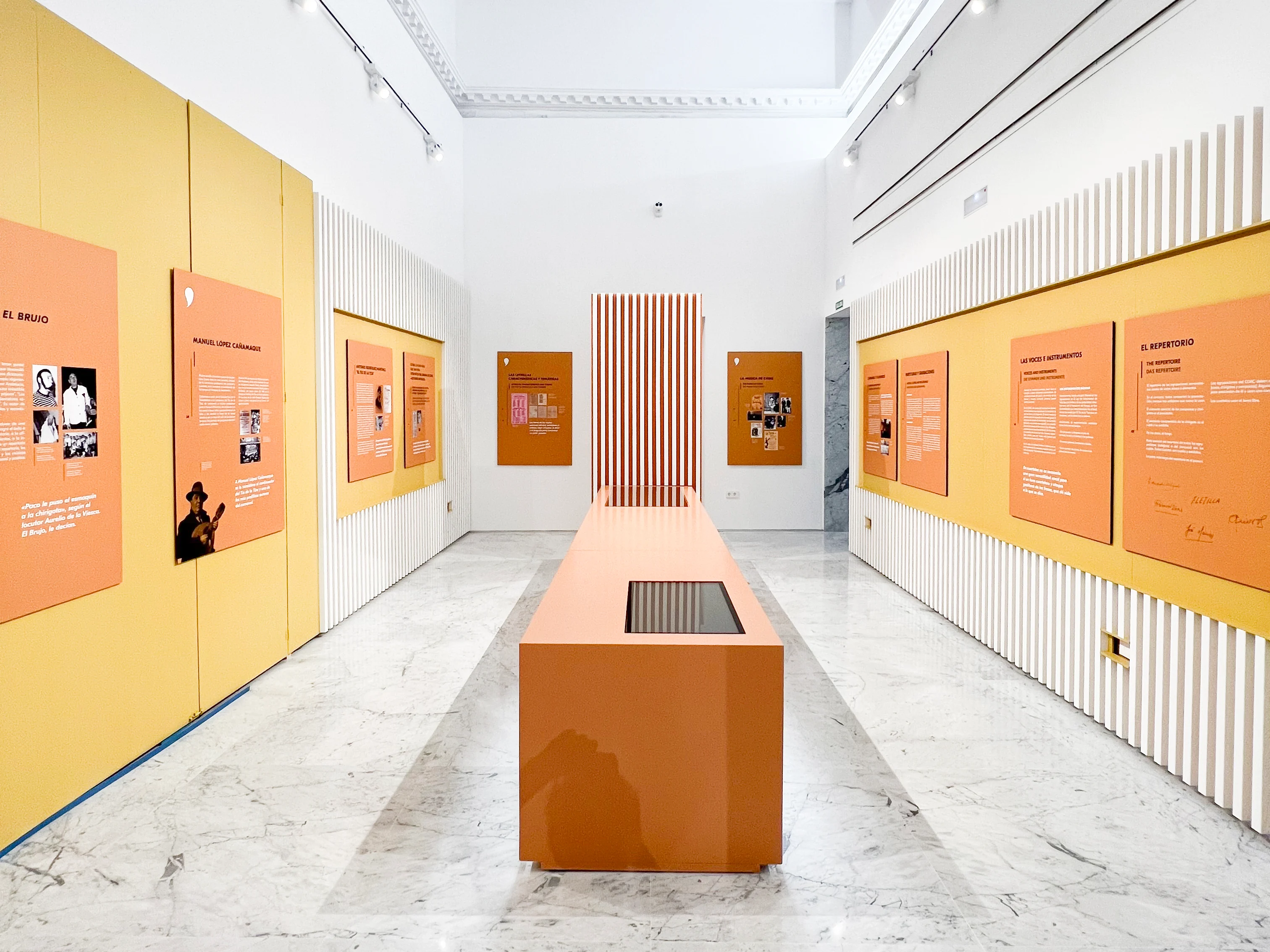 Sala de la Casa del Carnaval de Cádiz con paneles amarillos y naranjas y mobiliario expositivo